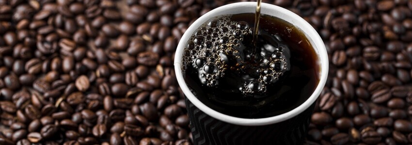 Americano med kaffebönor i bakgrunden